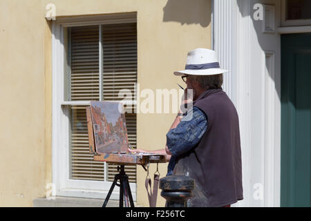 Artist painting the High Street scene on a bustling Saturday morning in Stony Stratford, Buckinghamshire, England Stock Photo