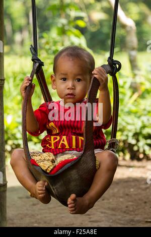 Indonesia, Sunda islands, Lombok, Joben, Young boy on a swing Stock Photo