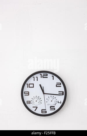 Big black round clock on white wall. Stock Photo