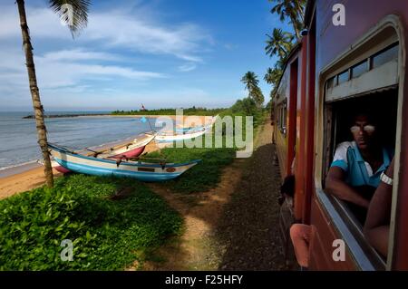 Sri Lanka, Western Province, train from Colombo to Galle, fishing boats on the beach along the railroad Stock Photo