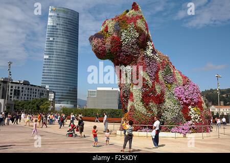 Spain, Biscay, Basque Country, Bilbao, Guggenheim Museum forecourt, Giant dog Puppy, sculpture more than 12 meters high by Jeff Koons and Iberdrola Tower in the background Stock Photo