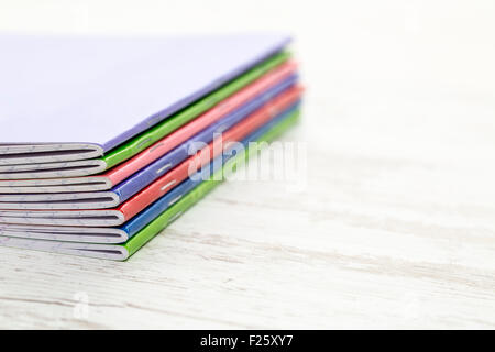 Image of a stack of colorful notebooks on a white wooden table. Stock Photo