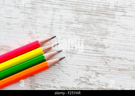 Upper view of four colorful graphite pencils on a white wooden table. Stock Photo