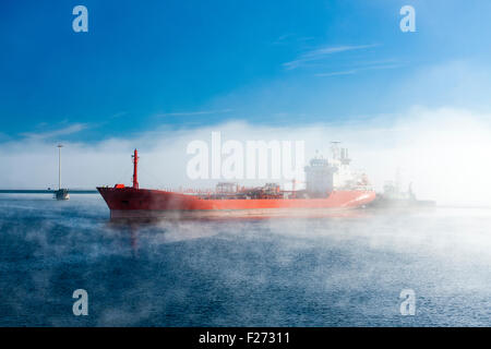 Tanker Escorted by Tug Arriving to Harbour on Foggy Morning. For Editorial Use Only. Stock Photo