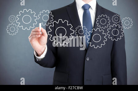 Businessman drawing gears with chalk Stock Photo