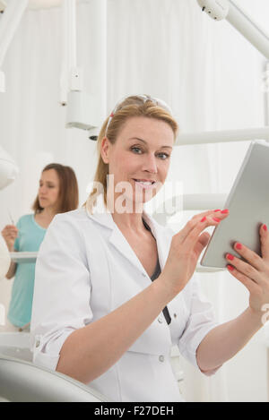Female dentist using digital tablet in clinic, Munich, Bavaria, Germany Stock Photo
