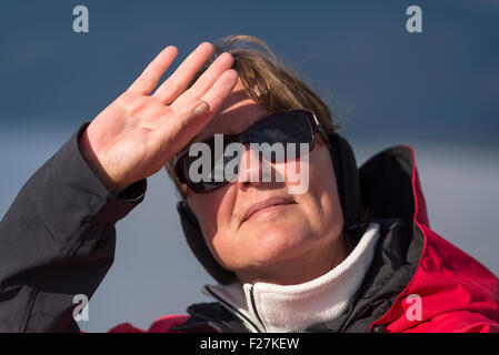 Woman shielding the sun from her eyes as she looks out. Stock Photo