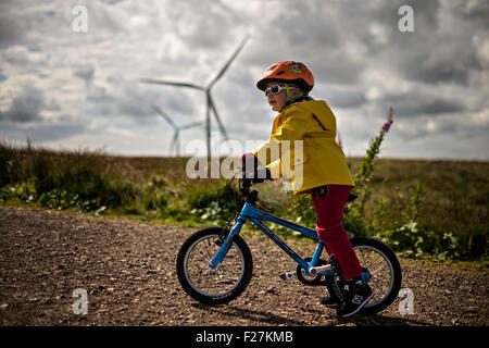 EAGLESHAM, SCOTLAND - AUGUST 28: a general view of a young male child cycling on a cycle track amongst wind turbines on Scottish Stock Photo