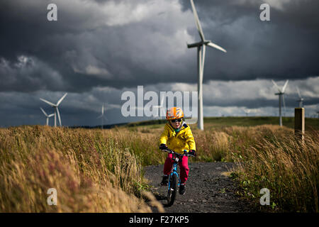 EAGLESHAM, SCOTLAND - AUGUST 28: a general view of a young male child cycling on a cycle track amongst wind turbines on Scottish Stock Photo