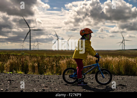 EAGLESHAM, SCOTLAND - AUGUST 28: a general view of a young male child cycling on a cycle track amongst wind turbines on Scottish Stock Photo