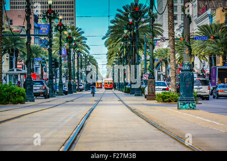 Looking down palm tree lined Canal street with tram tracks and distant streetcars and people in New Orleans, LA Stock Photo