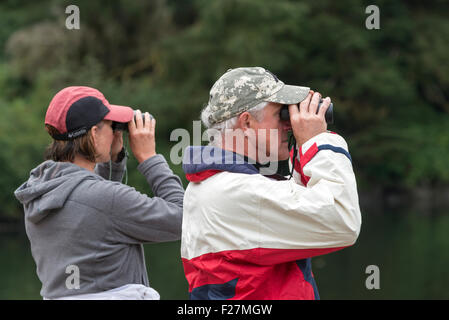 Couple using binoculars to watch wildlife in Alaska. Stock Photo