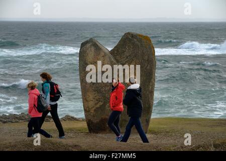 Walkers pass one of the prehistoric magaliths of Menhirs de Beg er Goalennec a.k.a. Bonnet d’Eveque. Quiberon, Brittany, France Stock Photo