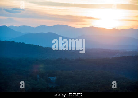 A setting sun peeks over the Blue Ridge Mountains in this scenic view from Asheville, North Carolina. Stock Photo