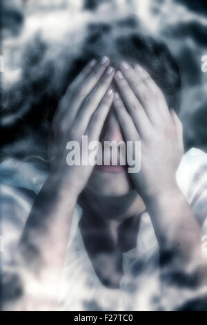 a woman in distress, hiding behind her hands Stock Photo