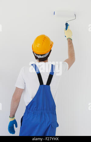 workman in helmet painting white wall Stock Photo