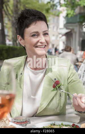 Mature woman having breakfast in sidewalk cafe, Bavaria, Germany Stock Photo