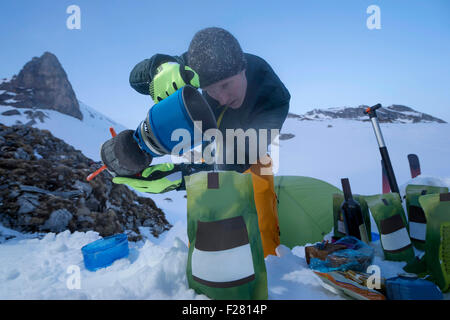 Man preparing ready meals to the bivouac camp, Tyrol, Austria Stock Photo