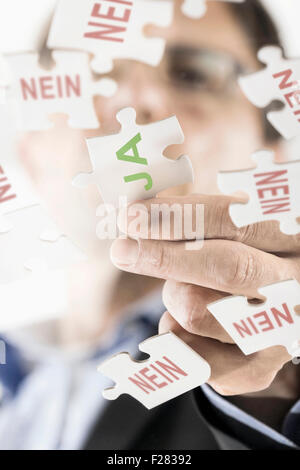 businessman arranging jigsaw puzzle pieces, Bavaria, Germany Stock Photo