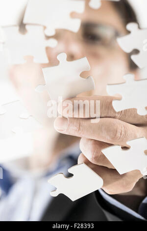businessman arranging jigsaw puzzle pieces, Bavaria, Germany Stock Photo