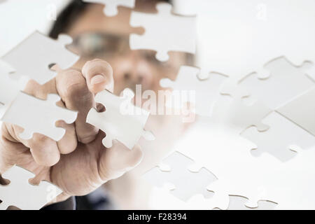 businessman arranging jigsaw puzzle pieces, Bavaria, Germany Stock Photo