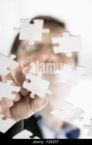 businessman arranging jigsaw puzzle pieces, Bavaria, Germany Stock Photo