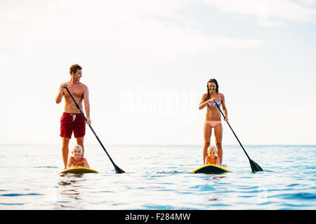 Family Having Fun Stand Up Paddling Together in the Ocean on Beautiful Sunny Morning Stock Photo