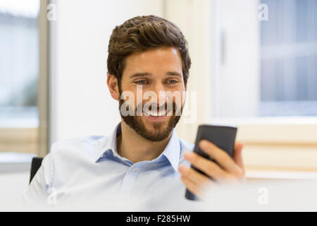 Cheerful bearded man making a video conference using his smartphone Stock Photo