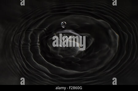 Drop of water falling on black water Stock Photo