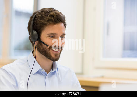 bearded man wearing headset using computer Stock Photo