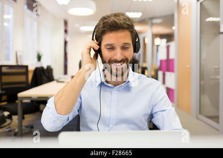 portrait of smiling business man wearing headset using laptop Stock Photo