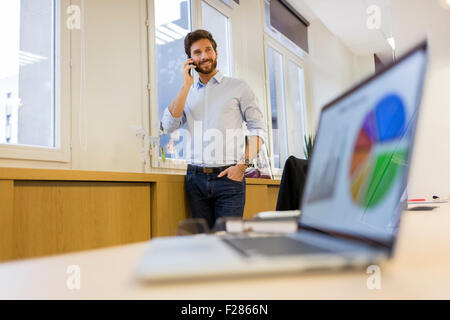 Businessman talking on cell phone in office. Stock Photo