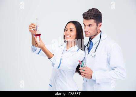Portrait of a two medical workers looking at tube with liquid isolated on a white background Stock Photo