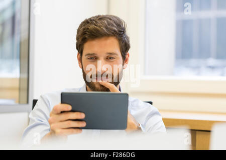 pensive businessman in office using digital tablet Stock Photo