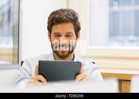 Cheering businessman in office using digital tablet Stock Photo