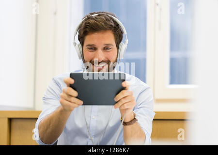 Creative businessman listening to headphones and using digital tablet. Stock Photo