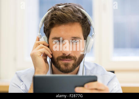 Creative businessman listening to headphones and using digital tablet. Stock Photo