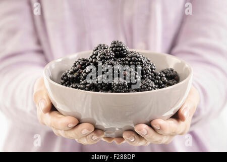 Mid section view of woman holding a bowl of blackberry, Bavaria, Germany Stock Photo