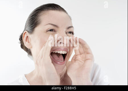 Mature woman shouting and screaming isolated over white background, Bavaria, Germany Stock Photo