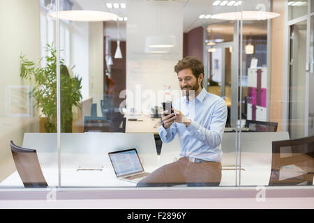 Hipster casual man. Typing text message  on mobile phone  in open space office Stock Photo