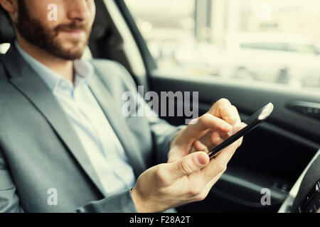 Man in car. Typing text message  on mobile phone Stock Photo