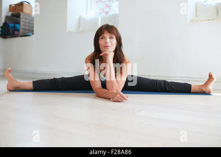 Fitness woman doing wide angle seated forward bend yoga workout at gym. Upavistha Konasana exercise. Caucasian woman doing the s Stock Photo