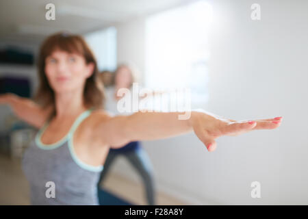 Woman stretching her arms at yoga class. Fitness trainer performing yoga in warrior pose. Virabhadrasana. Focus on hand. Stock Photo