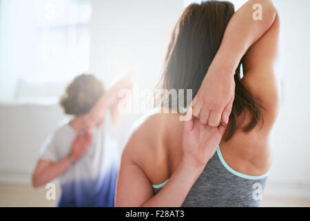 Rear view of fit woman doing gomukhasana in yoga class. Fitness female holding hands behind their back and stretching. Triceps a