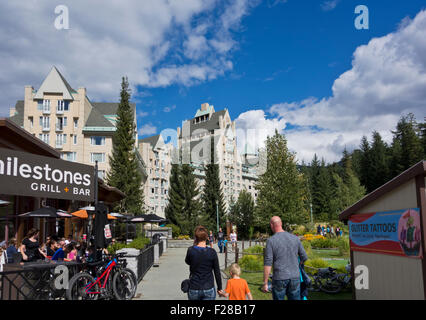 People dining at Milestones restaurant and walking towards Fairmont Chateau Whistler.  At Upper Village (Blackcomb) Whistler, BC Stock Photo