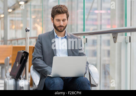 Casual business man working on laptop in airport hall Stock Photo