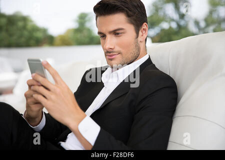 Portrait of a handsome man using smartphone outdoors in restaurant Stock Photo
