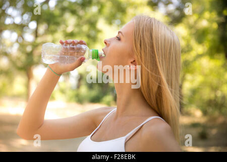 Portrait of attractive woman drinking water in park Stock Photo