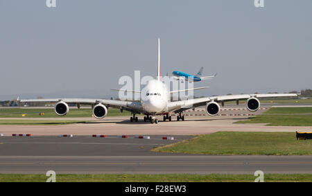 Emirates Airbus A380 double-decker passenger plane taxiing on Manchester Airport taxiway. KLM Boeing 737 on background. Stock Photo