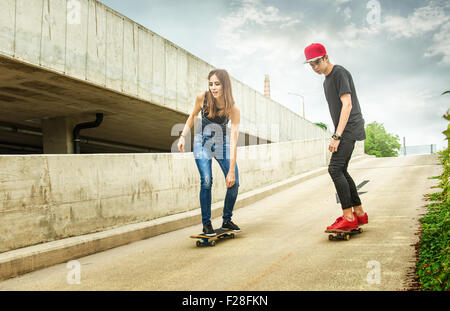 Skateboarder woman and man rolling down the slope Stock Photo